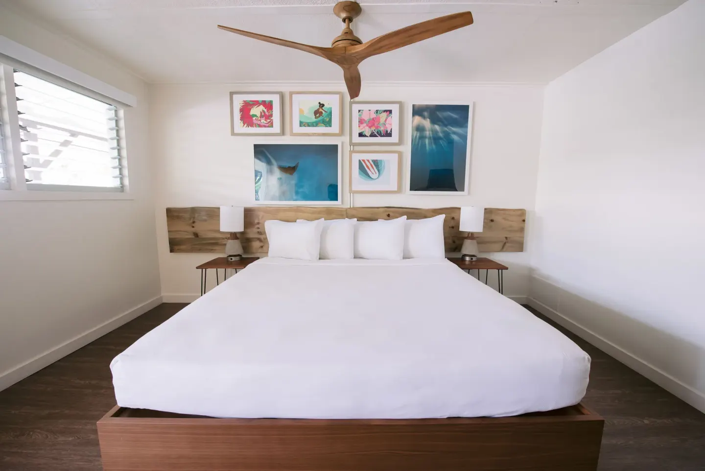King bed guest room with wood headboard and framed art at SCP Hilo Hotel.