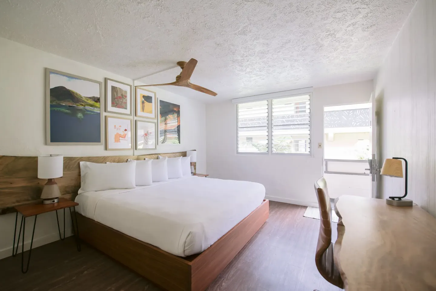 King bed guest room with desk, louvered windows, and open door at SCP Hilo Hotel.