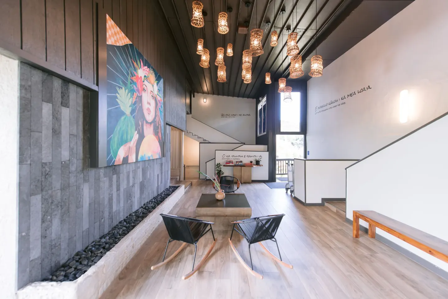 Lobby seating, pendant lights, wall art, and stairs inside SCP Hilo Hotel.