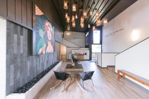 Lobby seating, pendant lights, wall art, and stairs inside SCP Hilo Hotel.