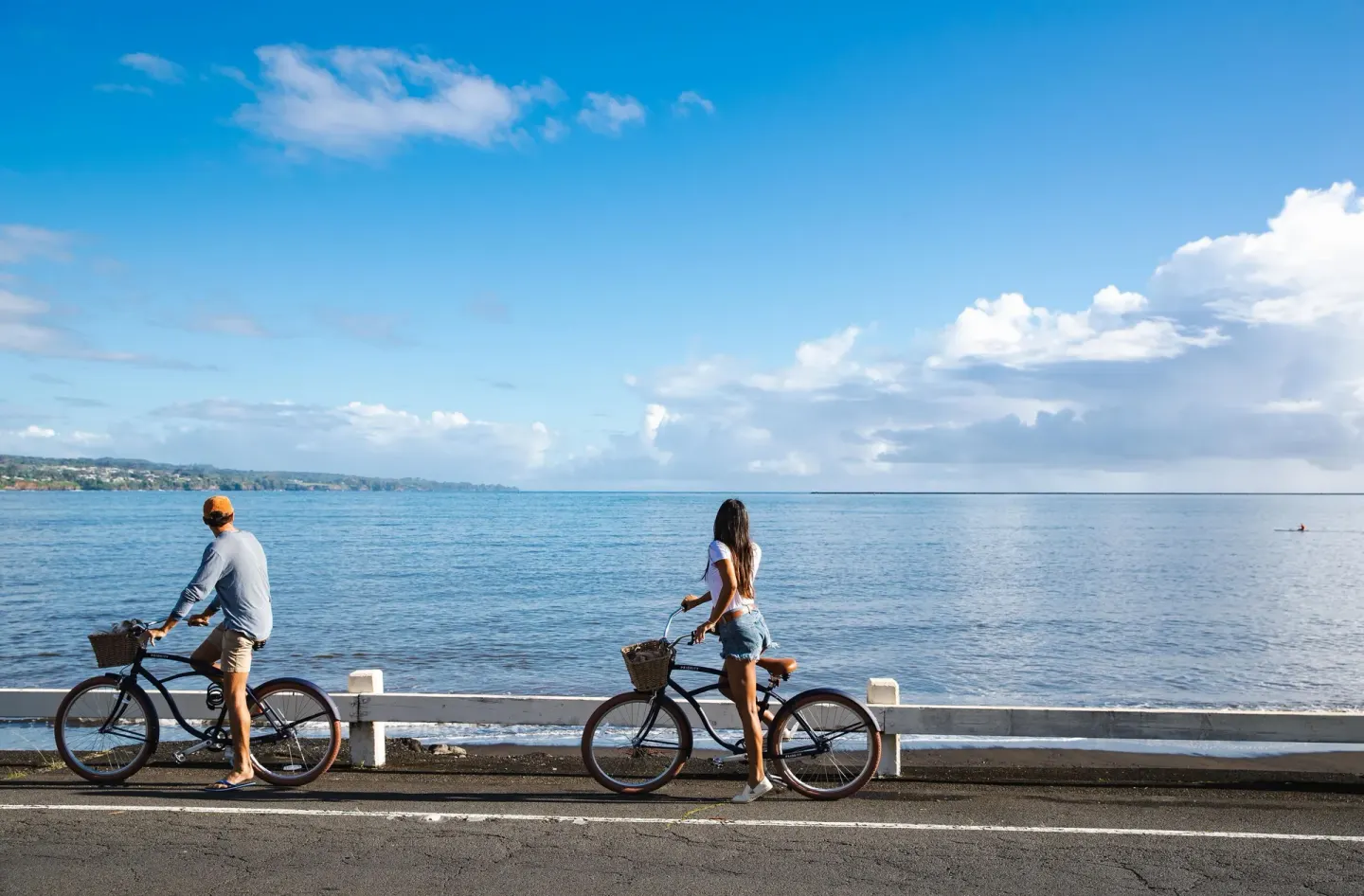 Two cyclists pause along the oceanfront road near SCP Hilo Hotel.