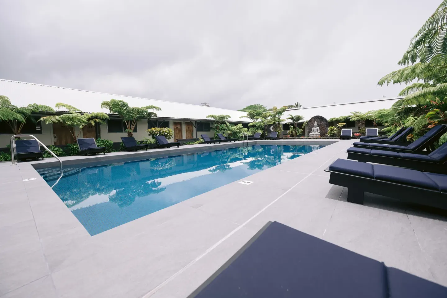 Outdoor pool with lounge chairs and tropical courtyard at SCP Hilo Hotel.