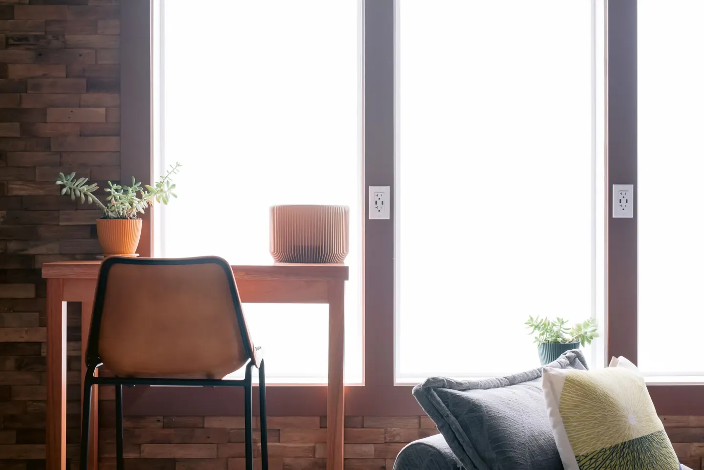 Window-side desk, chair, plants, and lounge cushion at SCP Hilo Hotel.