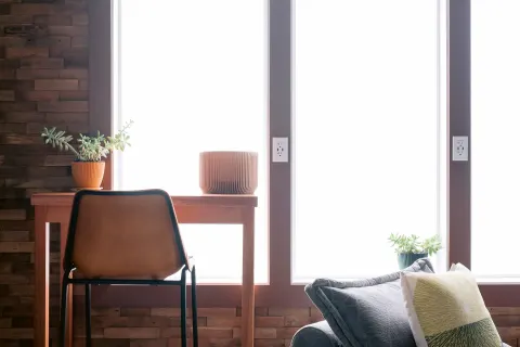 Window-side desk, chair, plants, and lounge cushion at SCP Hilo Hotel.
