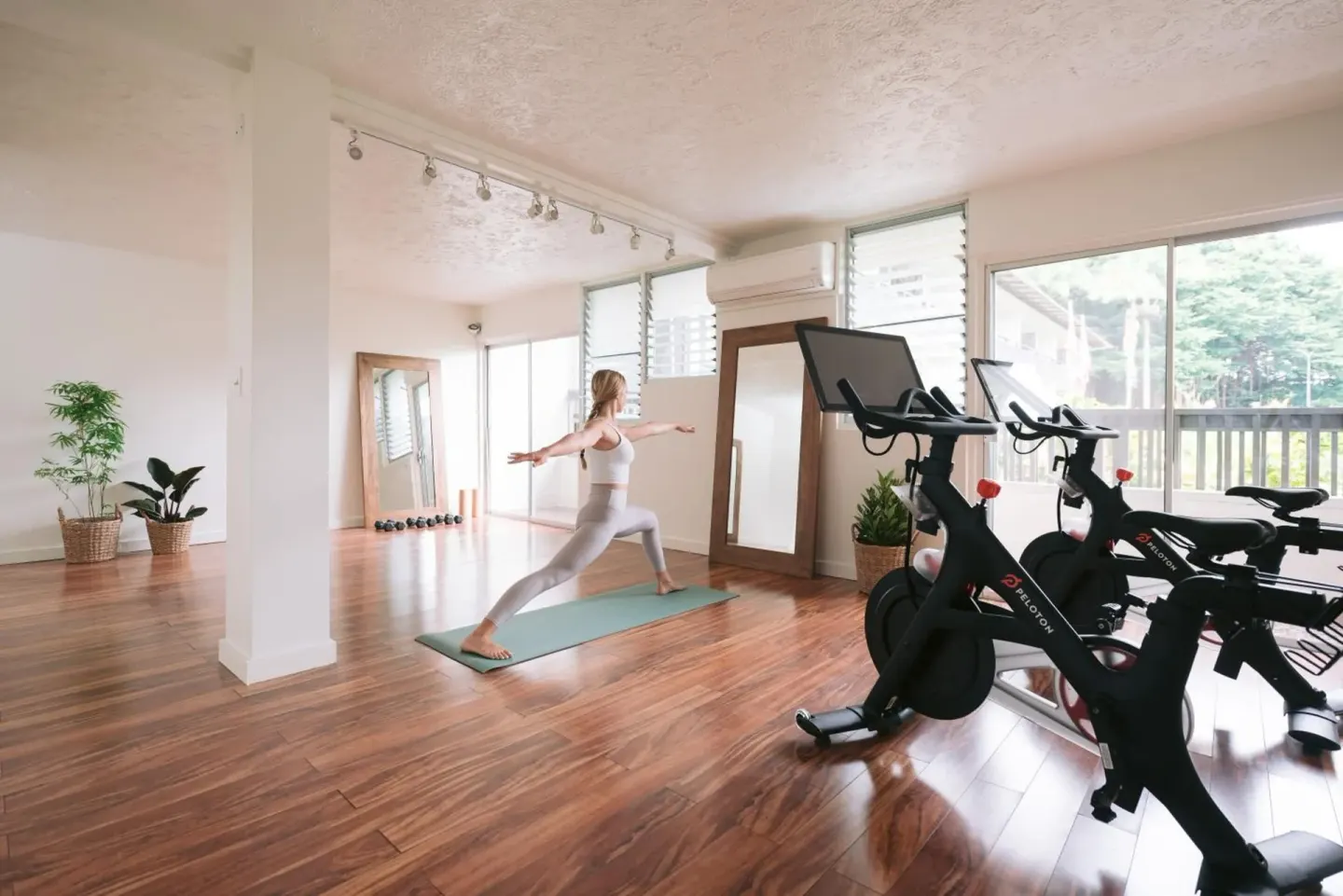 A guest practices yoga near stationary bikes in the fitness room at SCP Hilo Hotel.