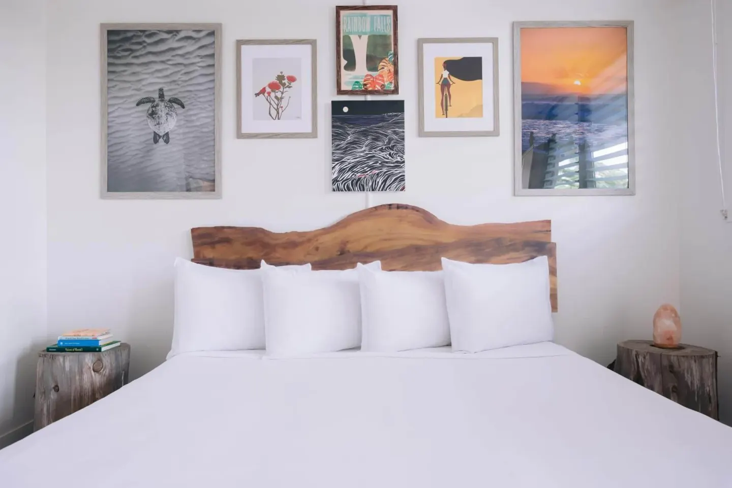 Peaceful Room bed with wood headboard and gallery wall at SCP Hilo Hotel.