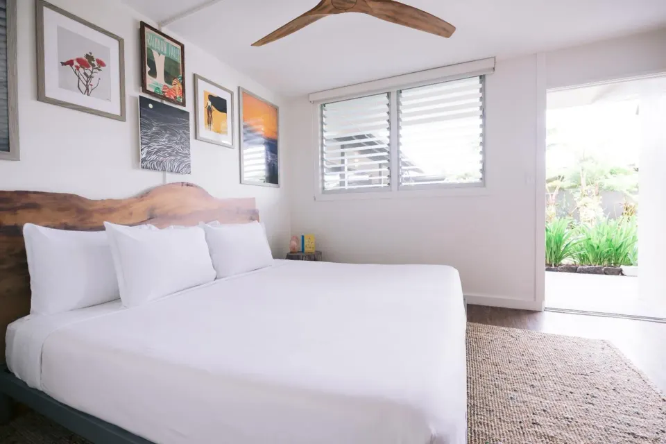 Peaceful Room with a bed, wall art, and patio door at SCP Hilo Hotel.
