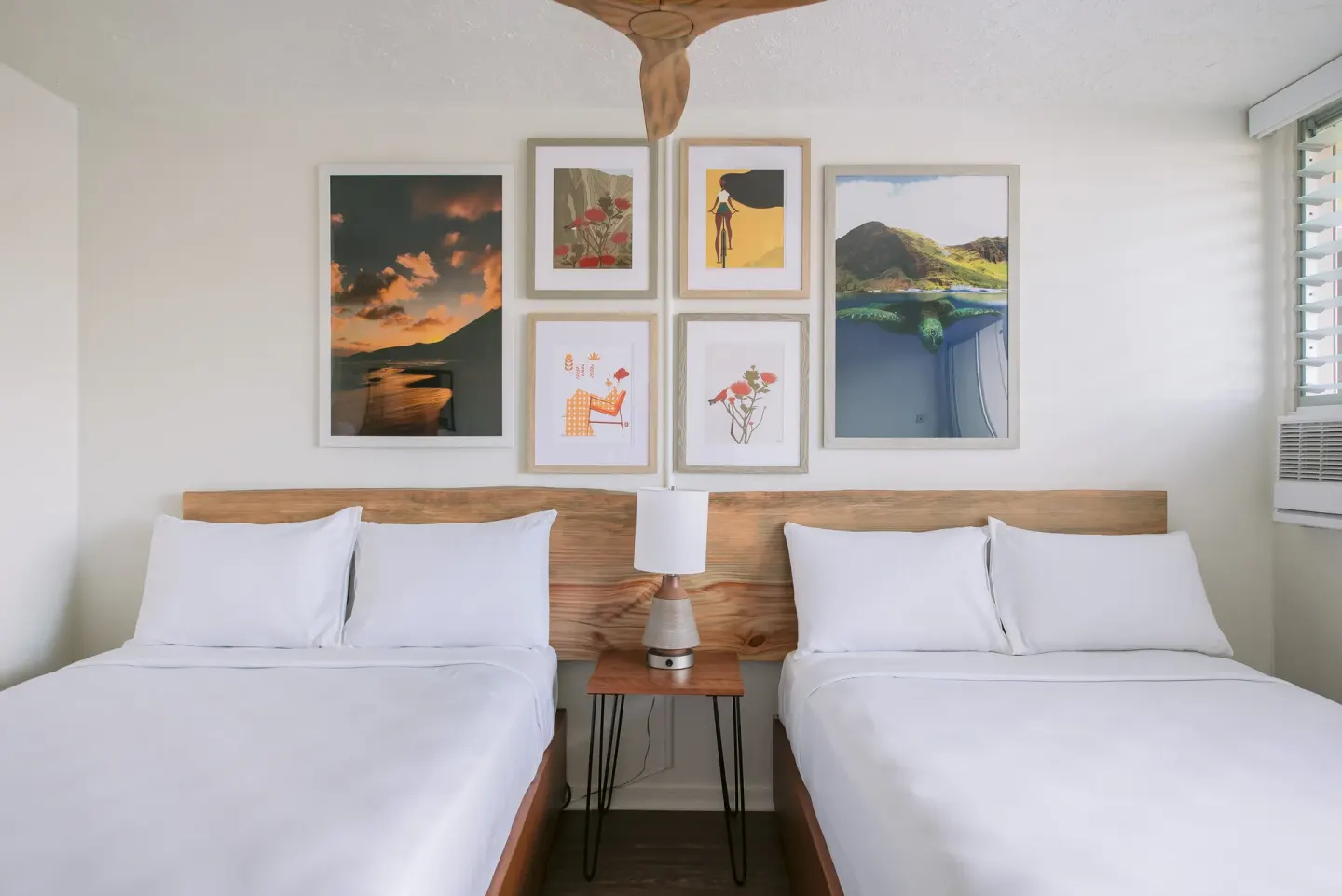 Peaceful Room with two beds, art, and a center nightstand at SCP Hilo Hotel.