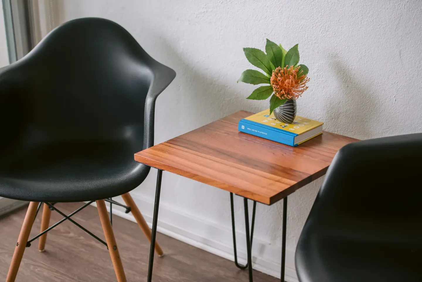 Guest room seating nook with two black chairs and a wood table at SCP Hilo Hotel.