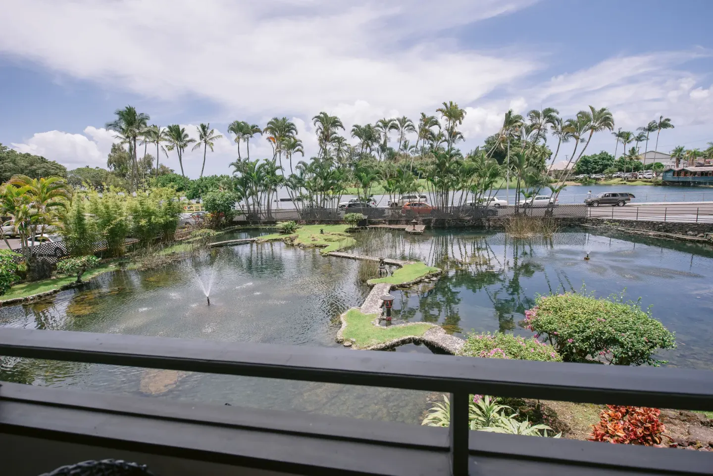 Balcony view over ponds, palms, and Hilo Bay from a room at SCP Hilo Hotel.