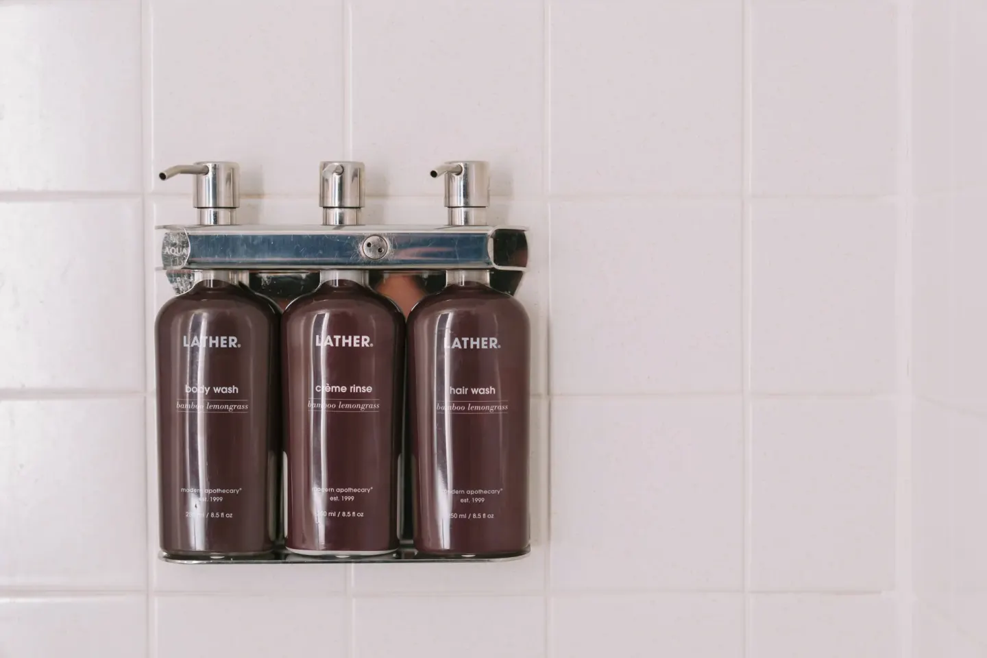 Wall-mounted bath amenities in a tiled guest bathroom at SCP Hilo Hotel.