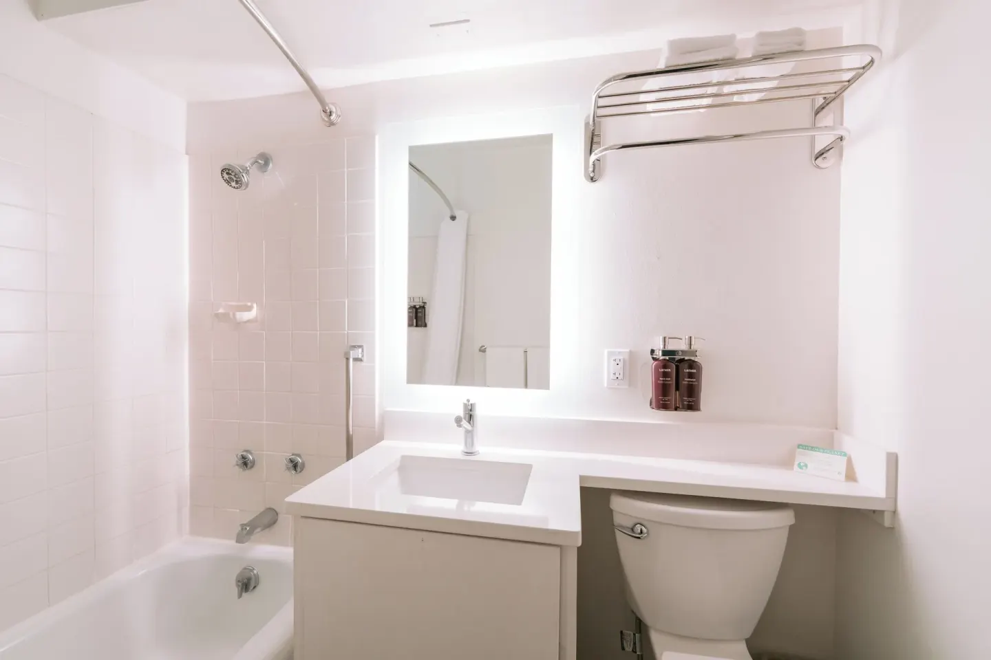 Guest room bathroom with tub, vanity, mirror, toilet, and towel rack at SCP Hilo Hotel.