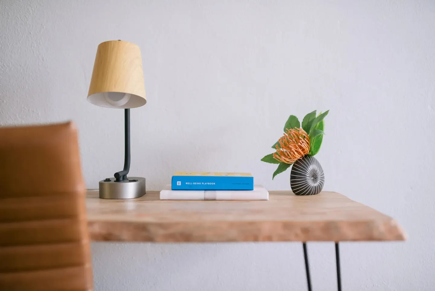 Guest room desk with lamp, chair, book, and flower arrangement at SCP Hilo Hotel.