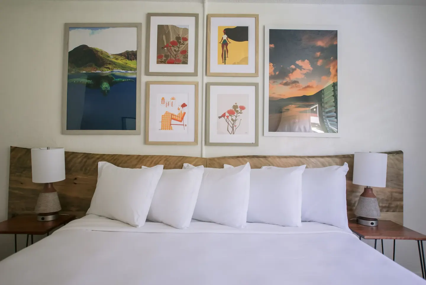 King bed with white pillows and framed art in a guest room at SCP Hilo Hotel.