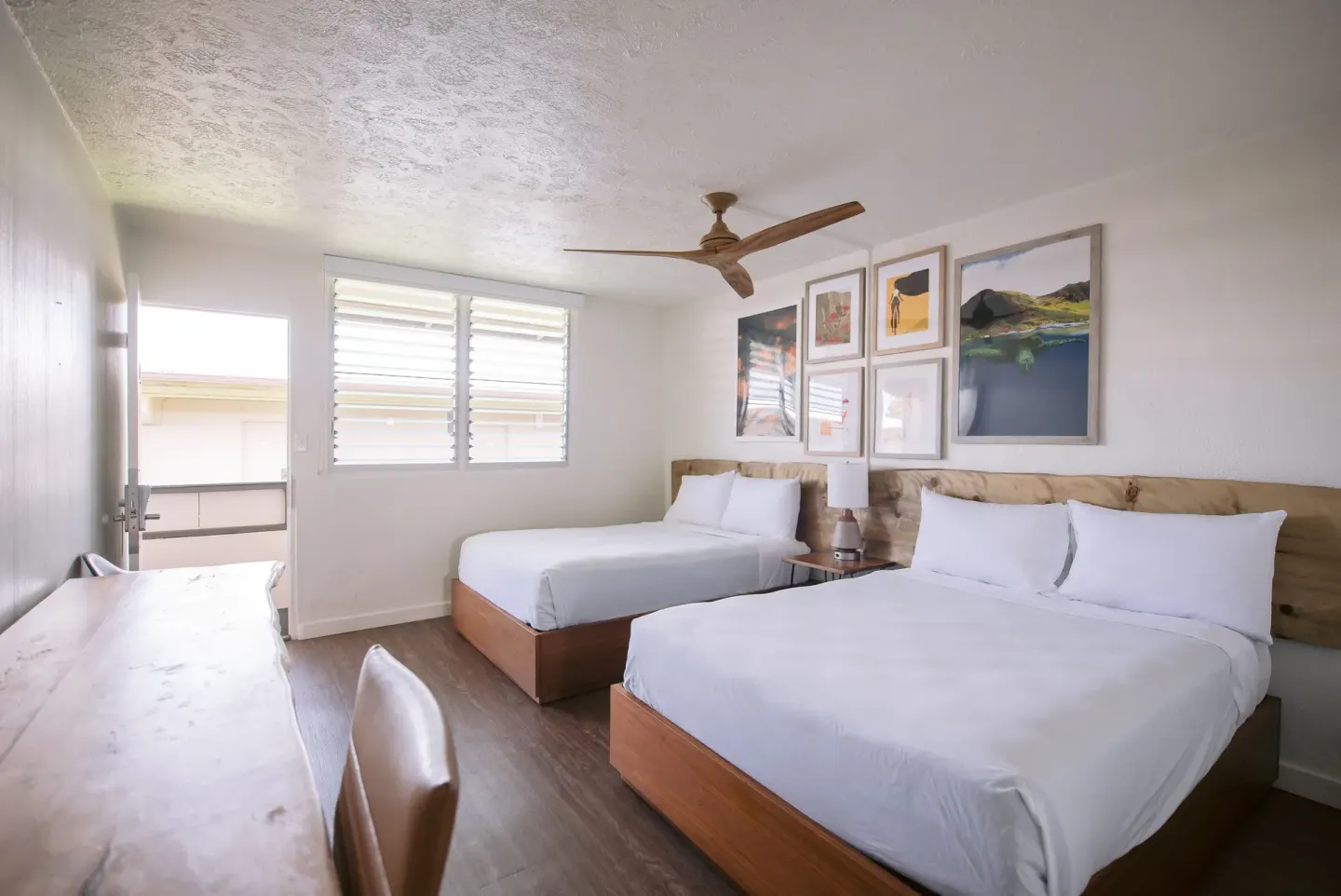 Two-bed guest room with desk, louvered windows, and wall art at SCP Hilo Hotel.