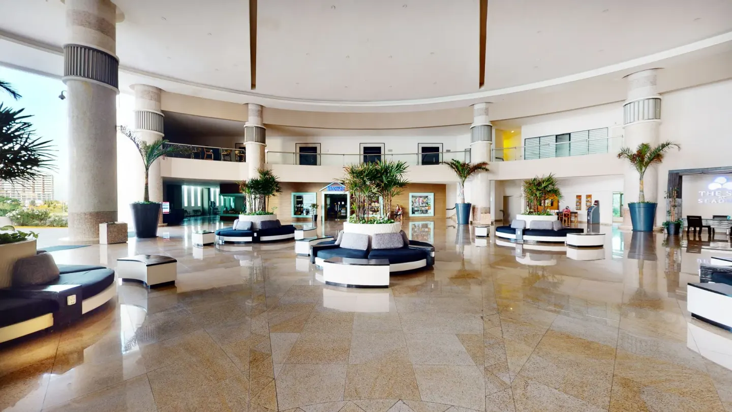Spacious circular lobby with sofas and palms at Seadust Cancún Family Resort.
