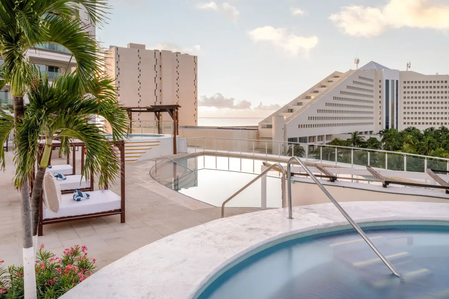Elevated pool area with palms and daybeds at Seadust Cancún Family Resort.