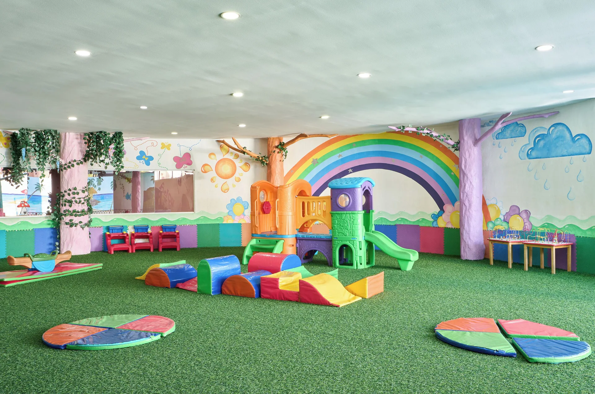 Indoor kids' play area with slides and rainbow mural at Seadust Cancún Family Resort.