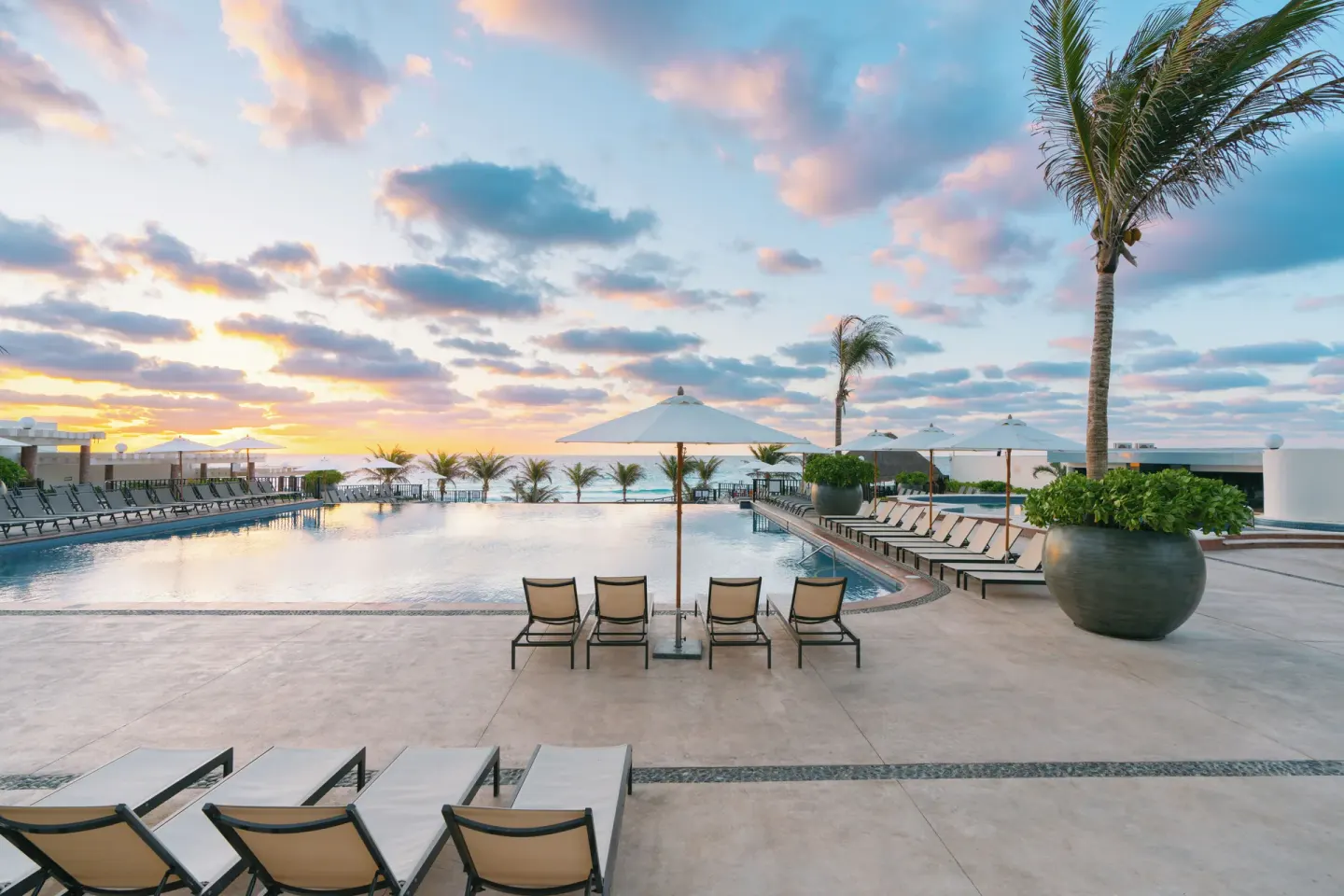 Pool deck with loungers and ocean views at Seadust Cancún Family Resort.