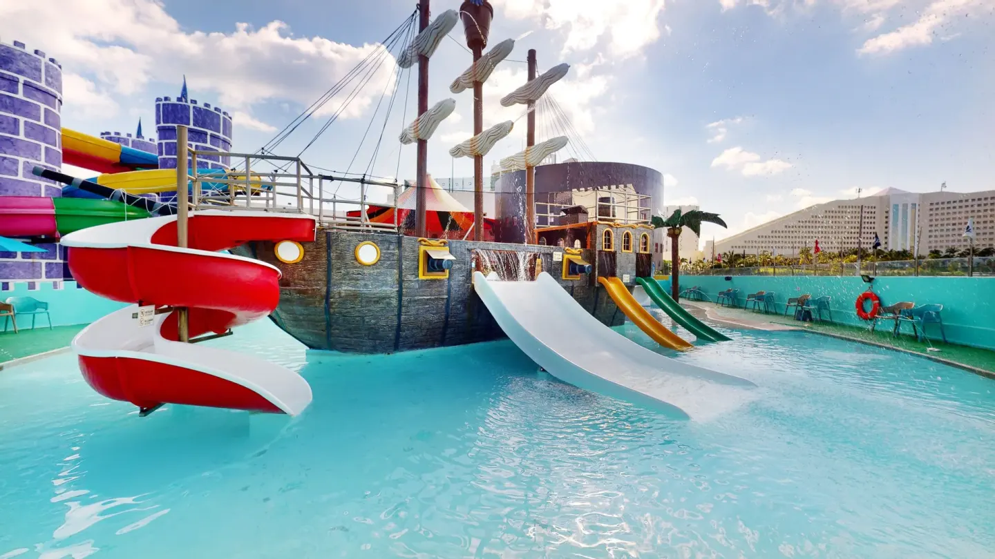 Pirate ship water playground with spiral and open slides at Seadust Cancún Family Resort.