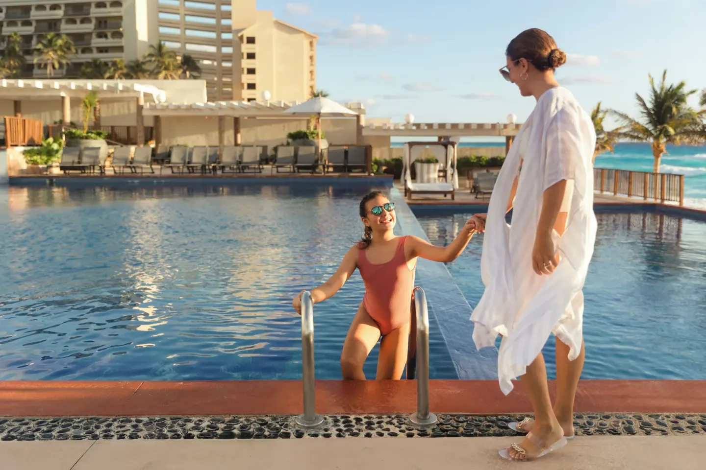 Adult helping a child out of the pool at Seadust Cancún Family Resort.
