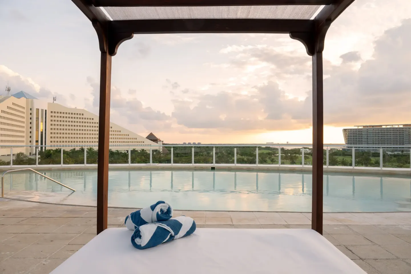 Canopy daybed facing a quiet pool at Seadust Cancún Family Resort.