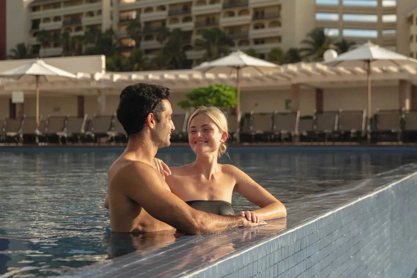 Couple relaxes in a pool with loungers behind them at Seadust Cancún Family Resort.
