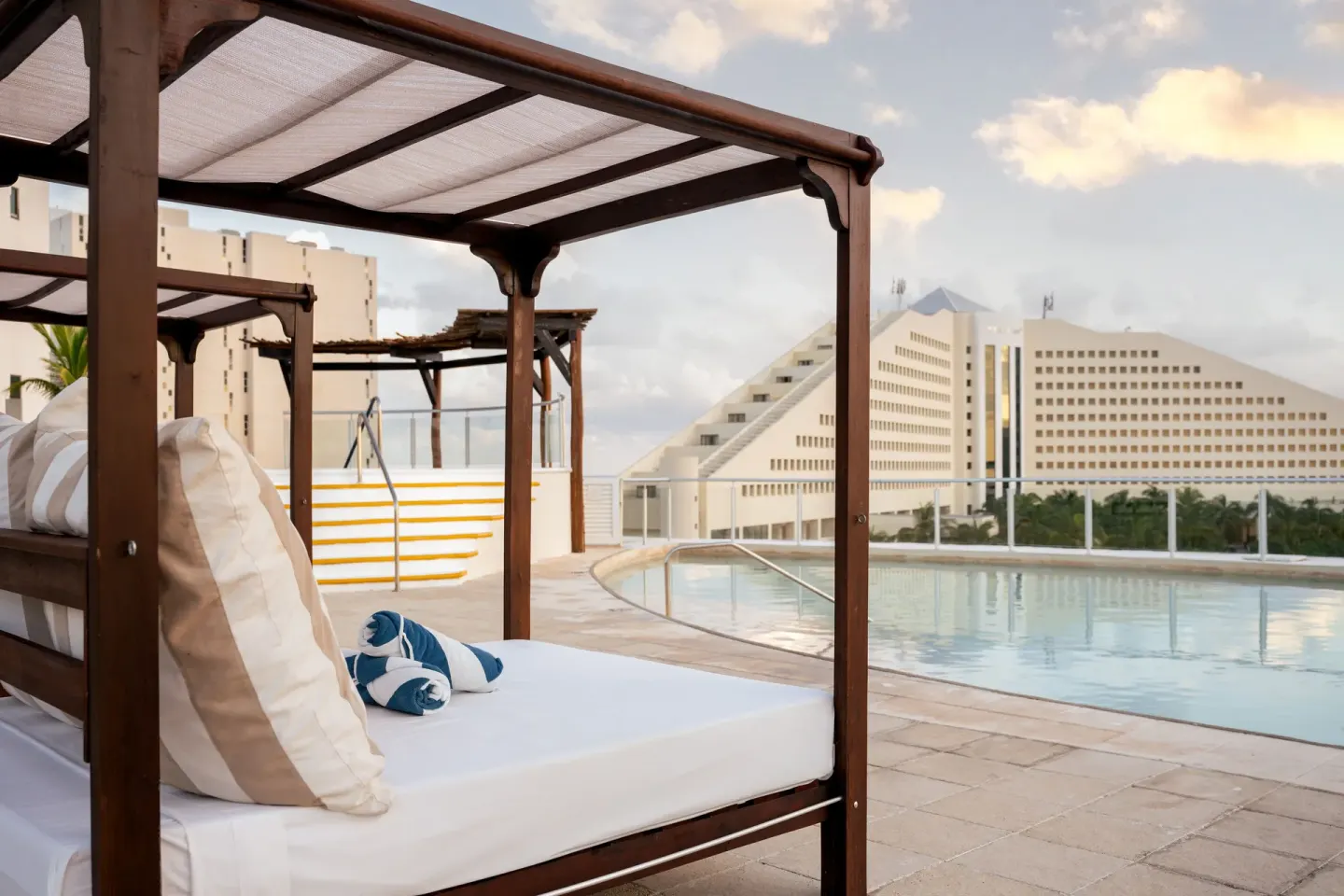 Canopy daybed beside a rooftop pool at Seadust Cancún Family Resort.