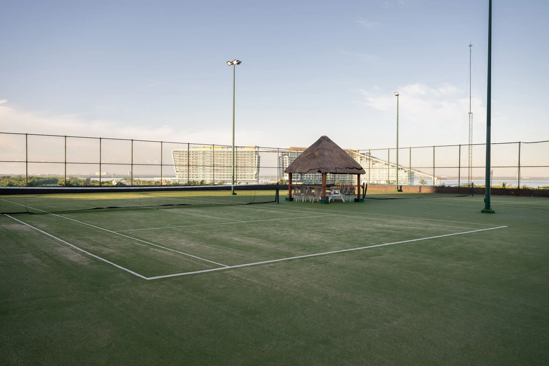 Rooftop tennis court with net and palapa seating at Seadust Cancún Family Resort.