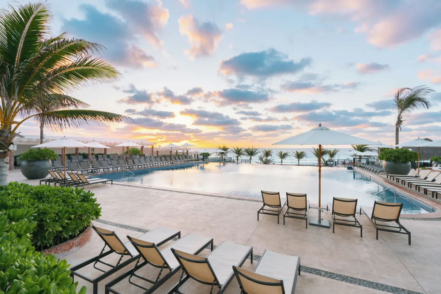Sunset pool deck with loungers and palms at Seadust Cancún Family Resort.