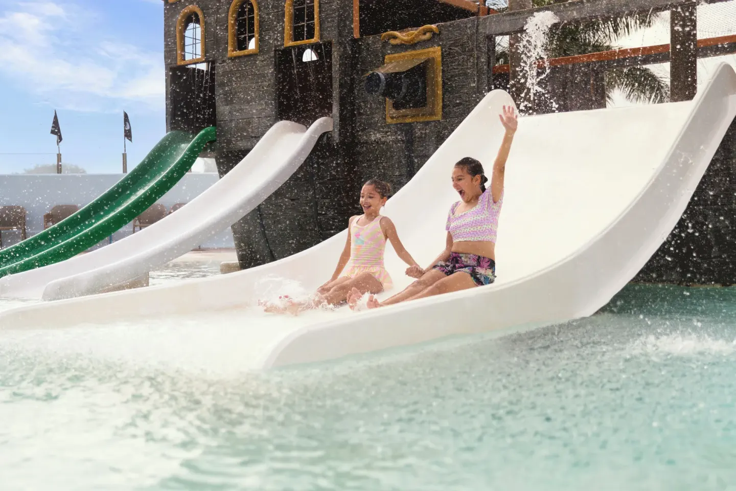 Two children ride a wide waterslide at Seadust Cancún Family Resort.