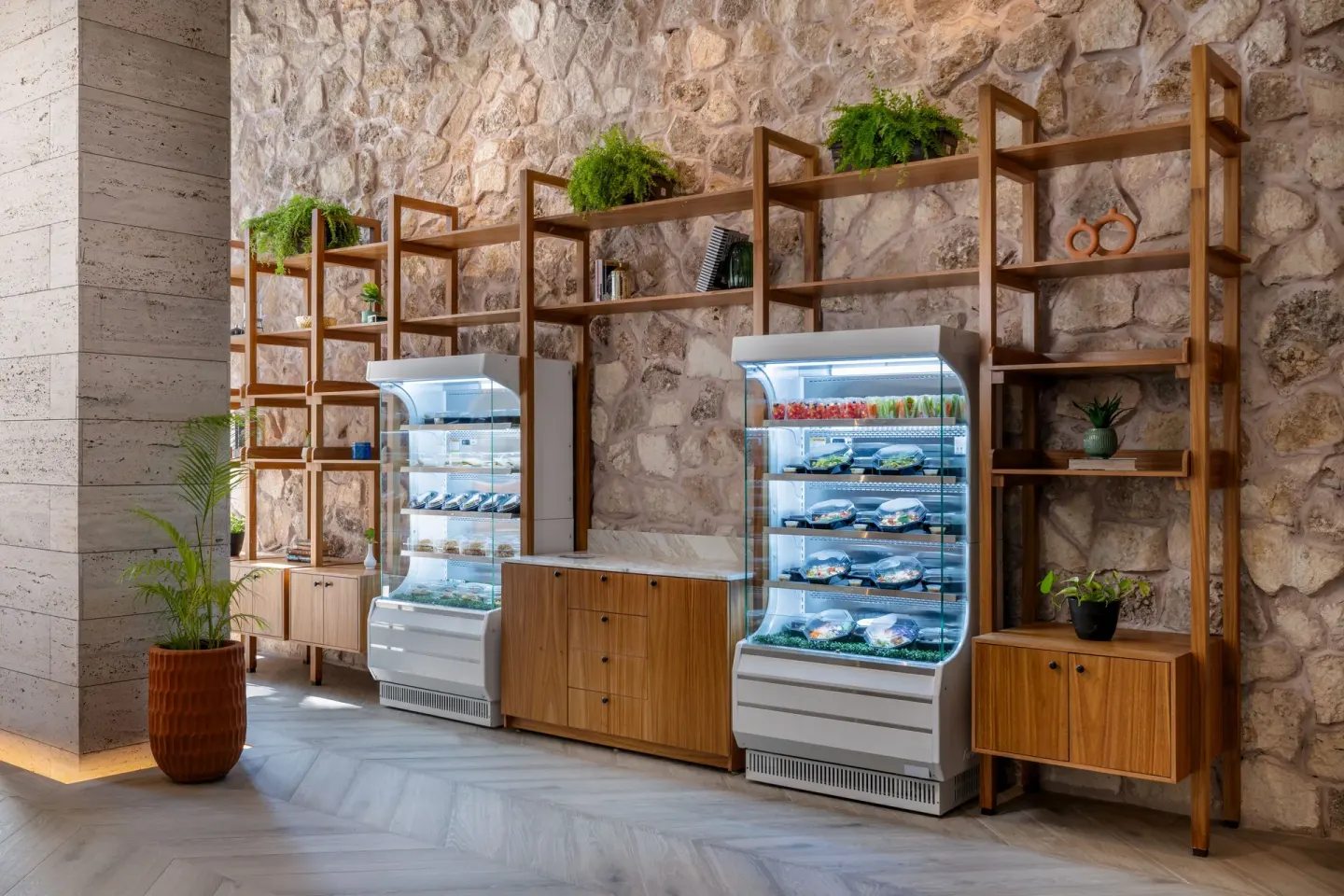 Refrigerated grab-and-go food cases set into a stone wall at Seadust Cancún Family Resort.
