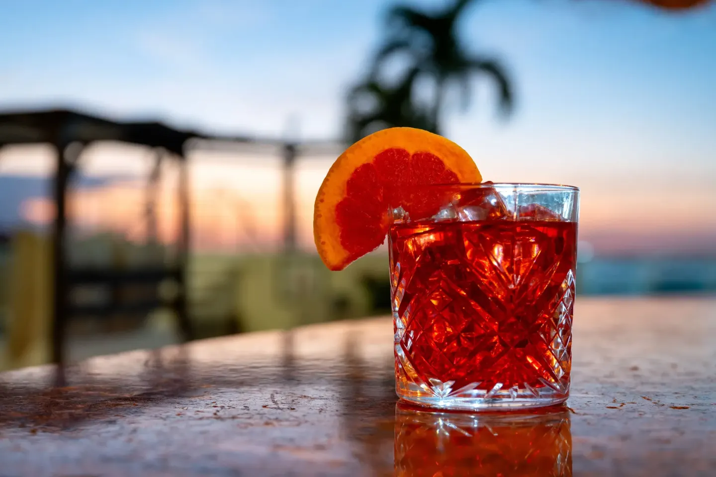 Red cocktail with orange garnish at sunset at Seadust Cancún Family Resort.