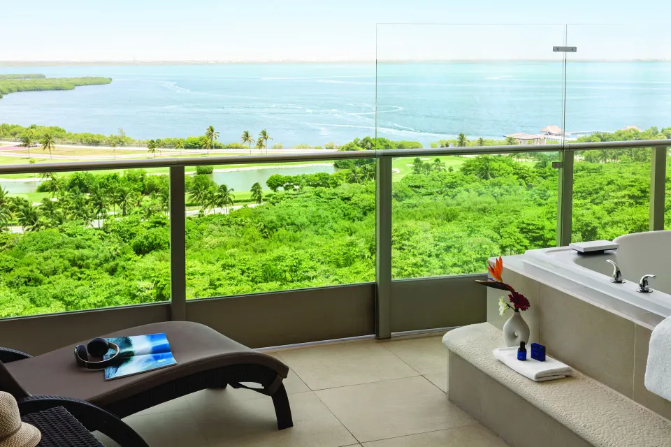 Deluxe Suite balcony with chaise lounge, soaking tub and lagoon view at Seadust Cancún Family Resort.