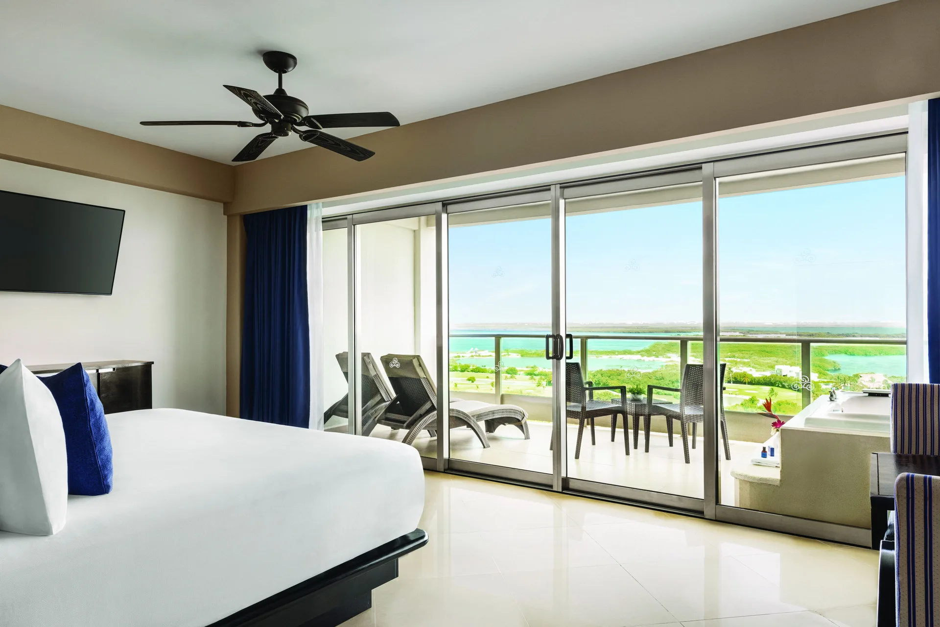 Deluxe Suite bed and balcony with lagoon view at Seadust Cancún Family Resort.