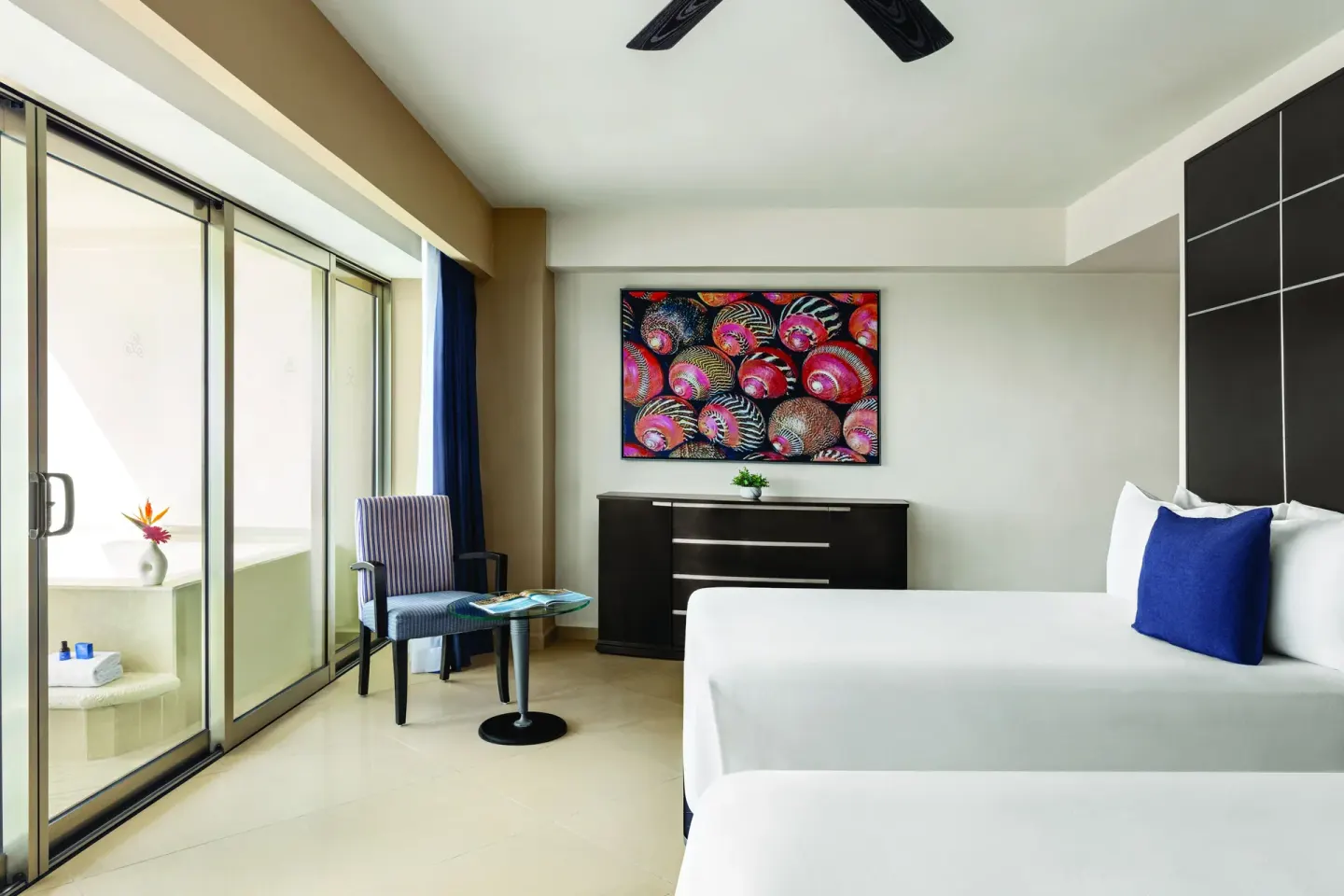 Deluxe Suite bedroom with two beds, dresser and balcony doors at Seadust Cancún Family Resort.