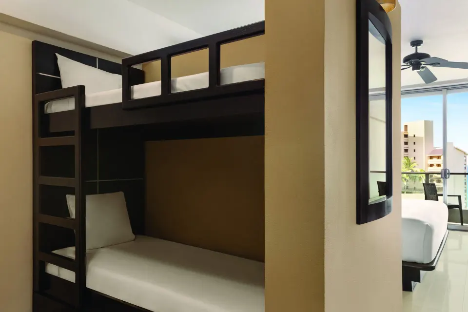 Family Suite bunk bed nook beside a mirror and balcony doors at Seadust Cancún Family Resort.