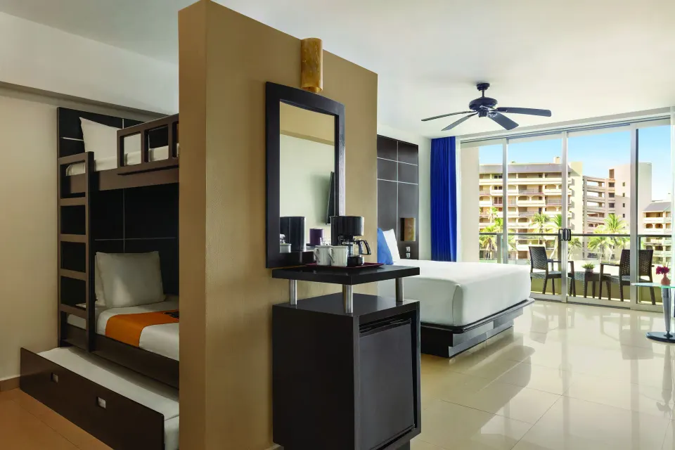 Family Suite with bunk beds, king bed, balcony, and refreshment area at Seadust Cancún Family Resort.