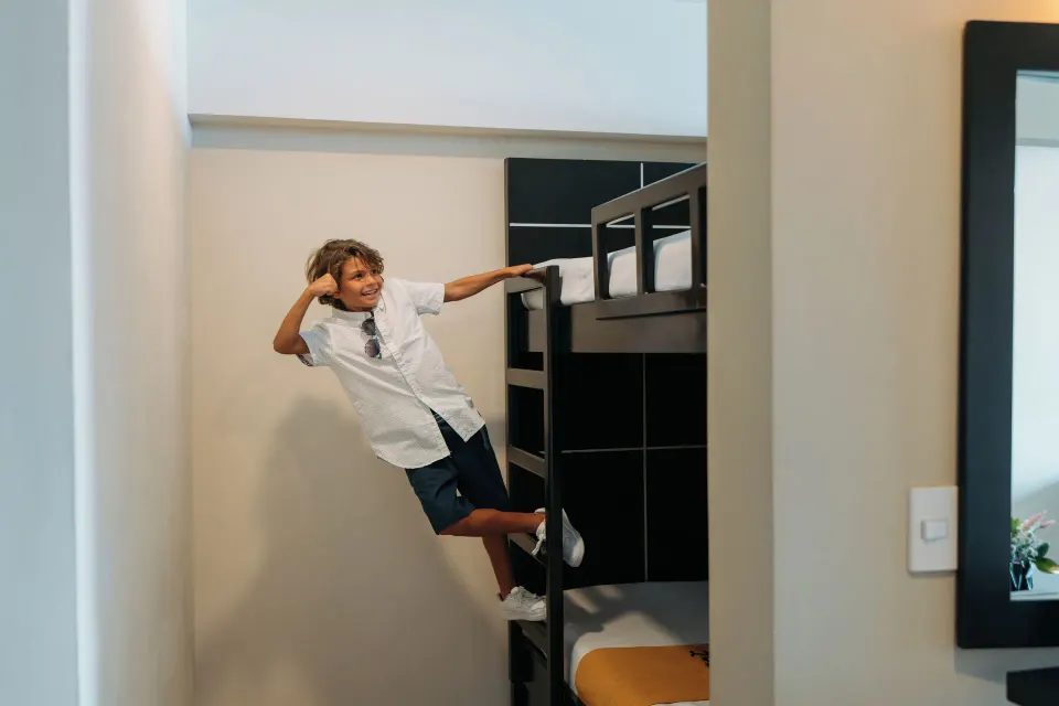 Child climbing the bunk bed ladder in a Family Suite at Seadust Cancún Family Resort.