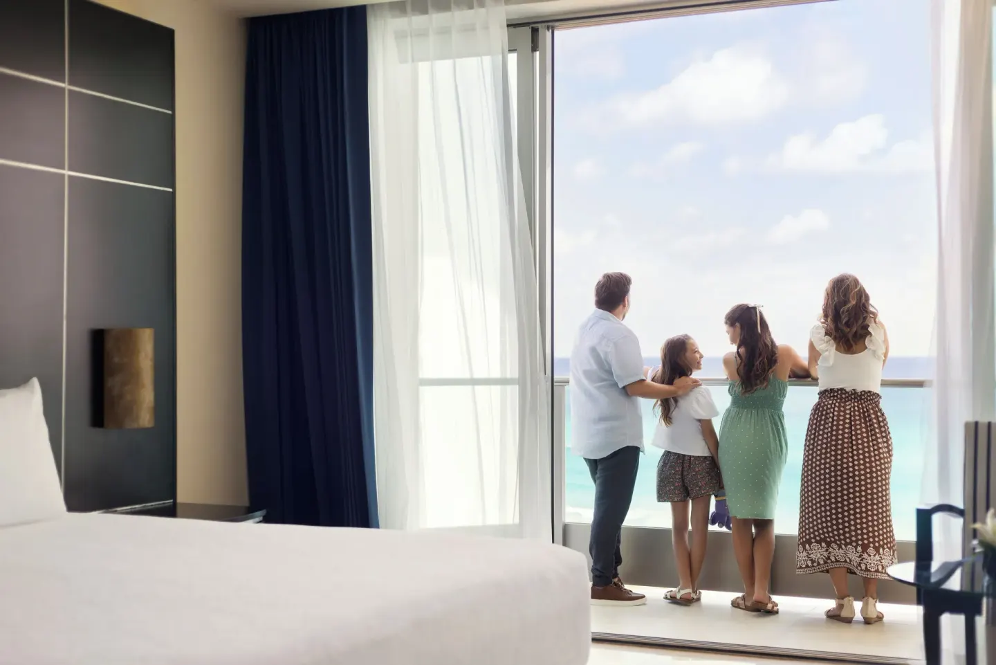 Family looking out from a Family Suite balcony at Seadust Cancún Family Resort.