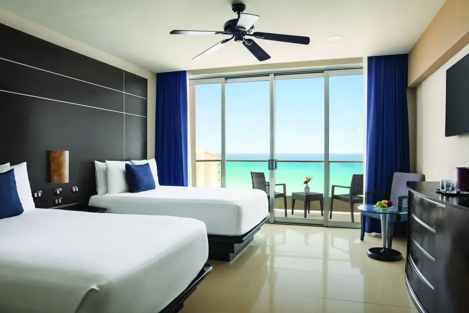 Family Suite with two beds and ocean-facing balcony at Seadust Cancún Family Resort.