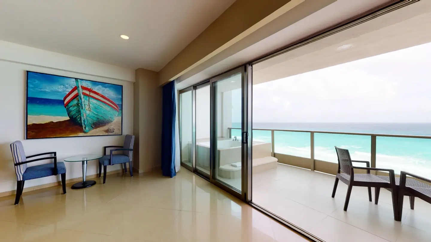 Oceanfront Suite sitting area beside a balcony and sea view at Seadust Cancún Family Resort.