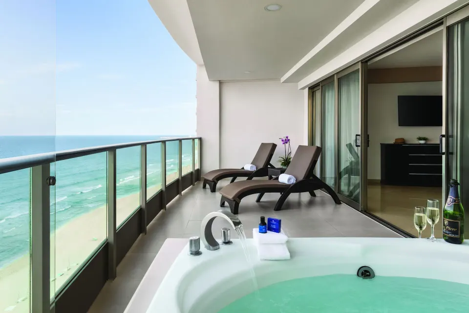Oceanfront Suite balcony with tub, loungers and sea view at Seadust Cancún Family Resort.