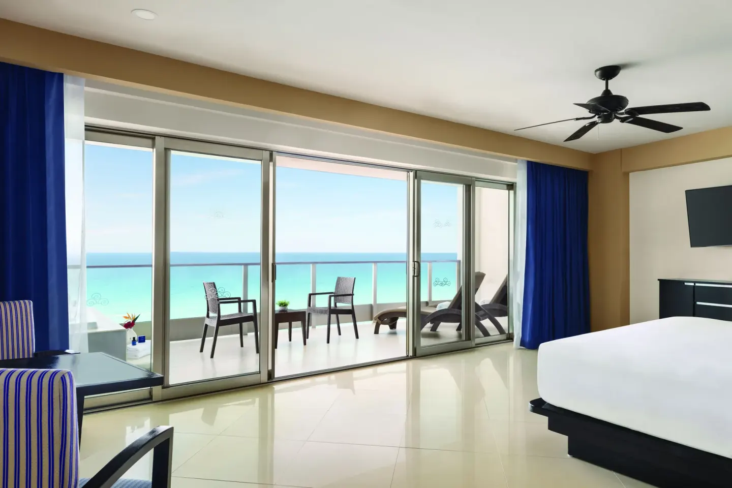 Oceanfront Suite king bed with balcony seating and ocean view at Seadust Cancún Family Resort.
