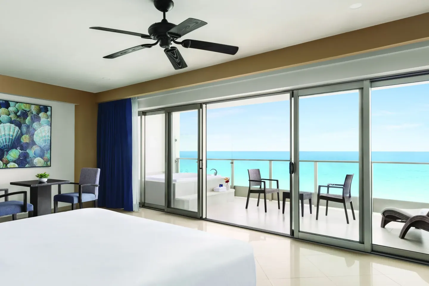 Oceanfront Suite king bed facing a wide balcony and turquoise sea at Seadust Cancún Family Resort.