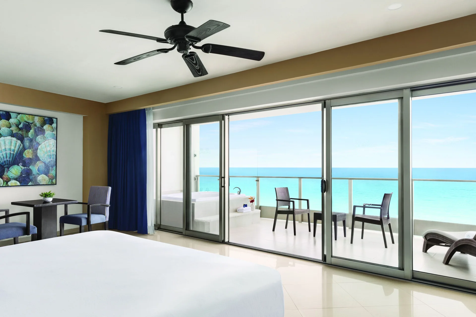 Oceanfront Suite king bed facing a wide balcony and turquoise sea at Seadust Cancún Family Resort.