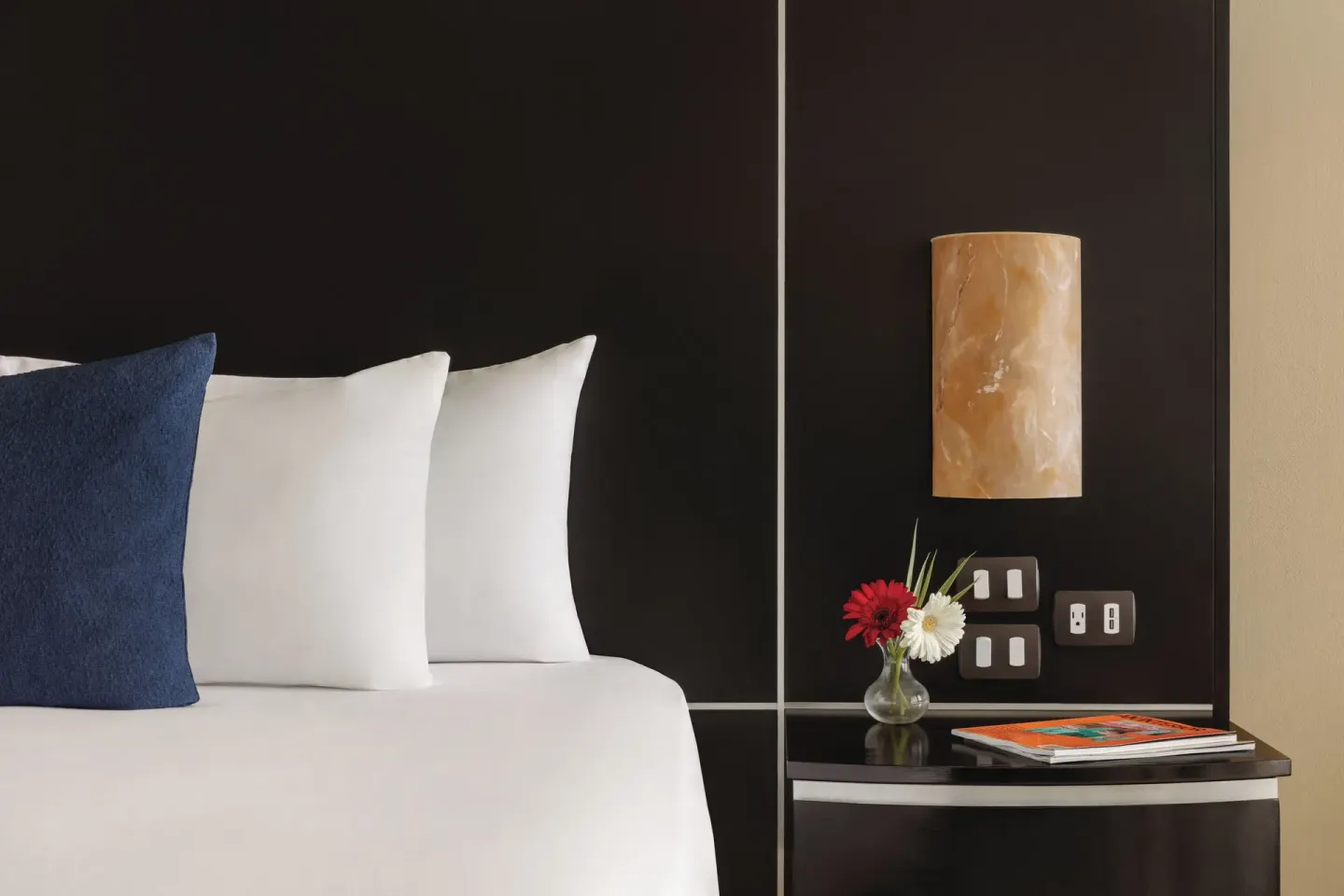 Oceanfront Suite bedside detail at Seadust Cancún Family Resort with pillows, lamp, and flowers.