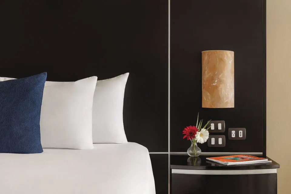 Oceanfront Suite bedside detail at Seadust Cancún Family Resort with pillows, lamp, and flowers.