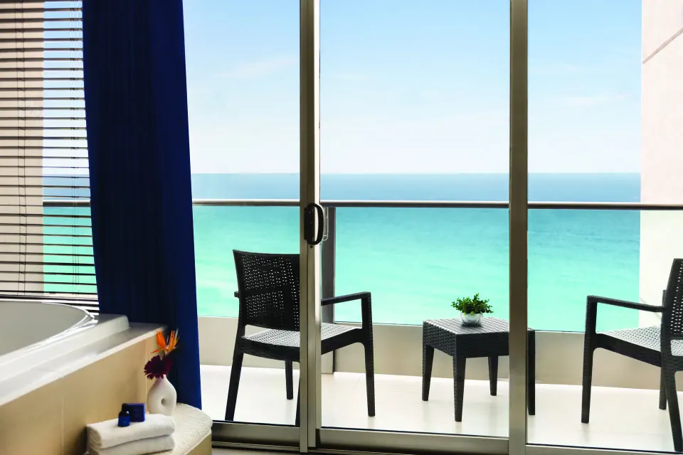 Premium Suite balcony seating and ocean view beside the soaking tub at Seadust Cancún Family Resort.