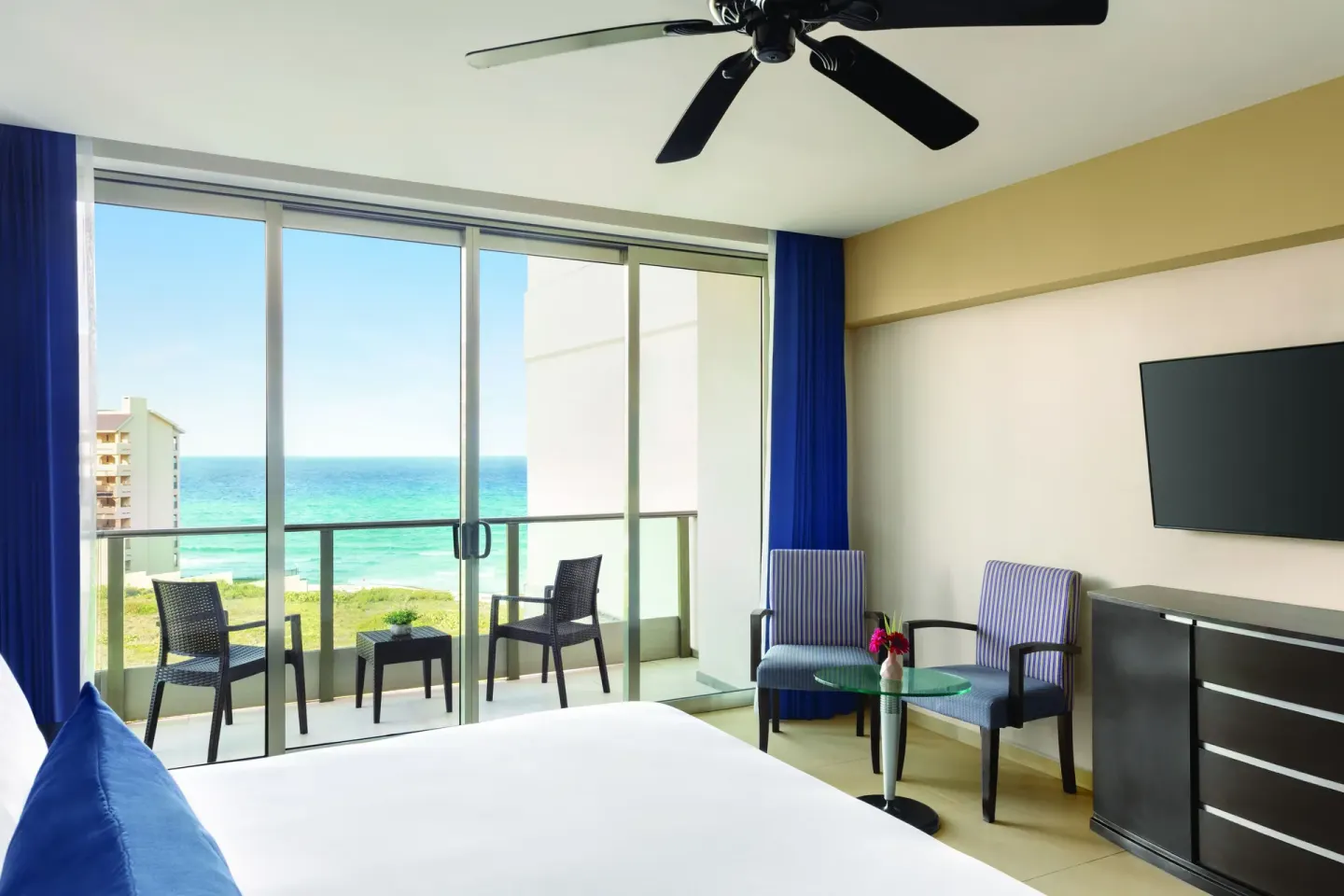 Standard Suite with king bed, balcony seating, and ocean view at Seadust Cancún Family Resort.
